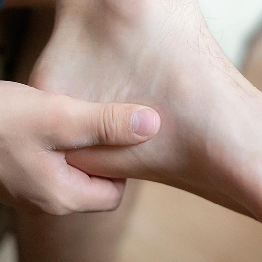 close-up of person holding heel while holding leg across other leg in seated position