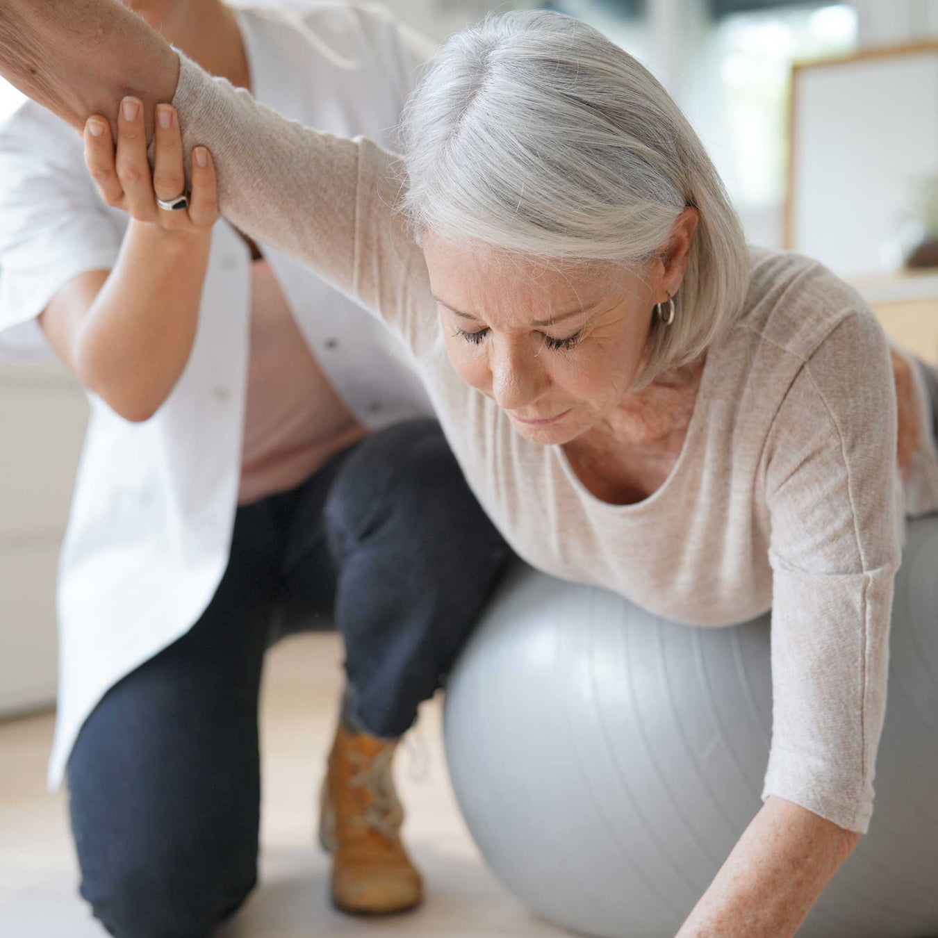 woman physical therapist assists her elderly patient with balance improving exercises