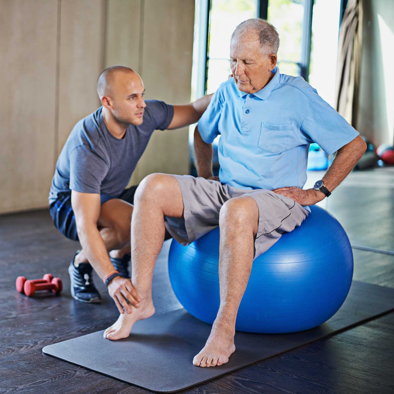 man physical therapist assists his elderly patient in rehabilitation exercises