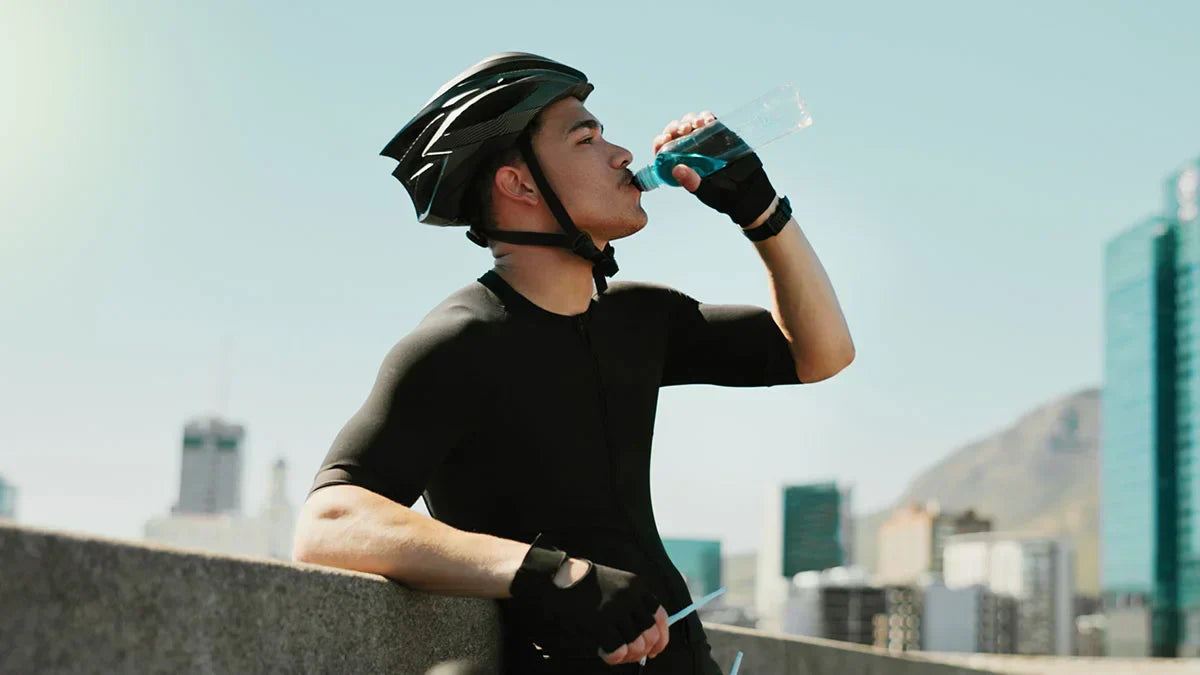 A biker drinks a blue electrolyte drink to rehydrate, showing the concept of the link between electrolytes and immune health.