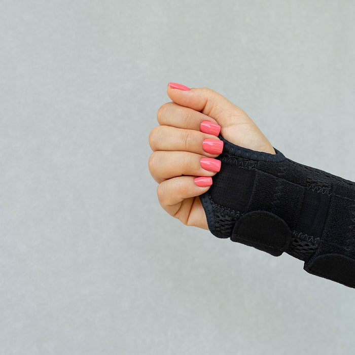 Forearm and hand with pink fingernails in black wrist brace with wrap closure