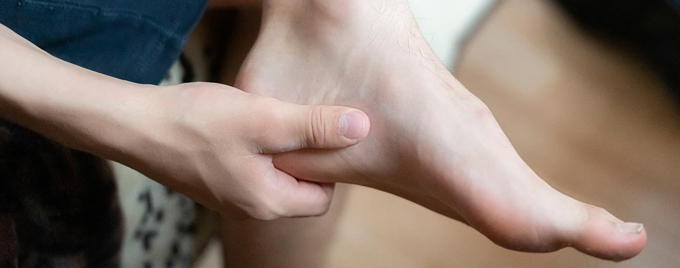close-up of person holding heel while holding leg across other leg in seated position