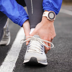 woman holds her ankle from pain after completing her run