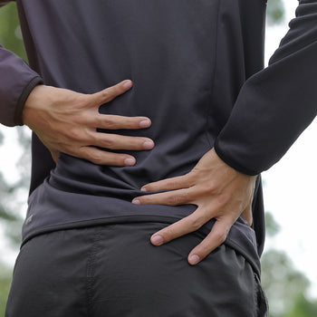 woman bracing her back from pain after finishing her run