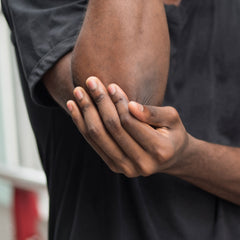 man rubbing his elbow to alleviate pain from tennis elbow