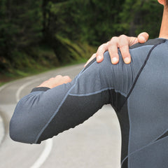 man rubbing his shoulder from pain while running