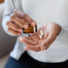 black woman pours 2 nutritional supplement pills into her open palm