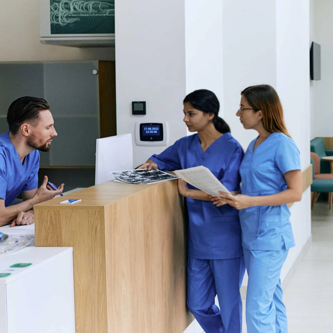 two doctors converse with an attending nurse over images