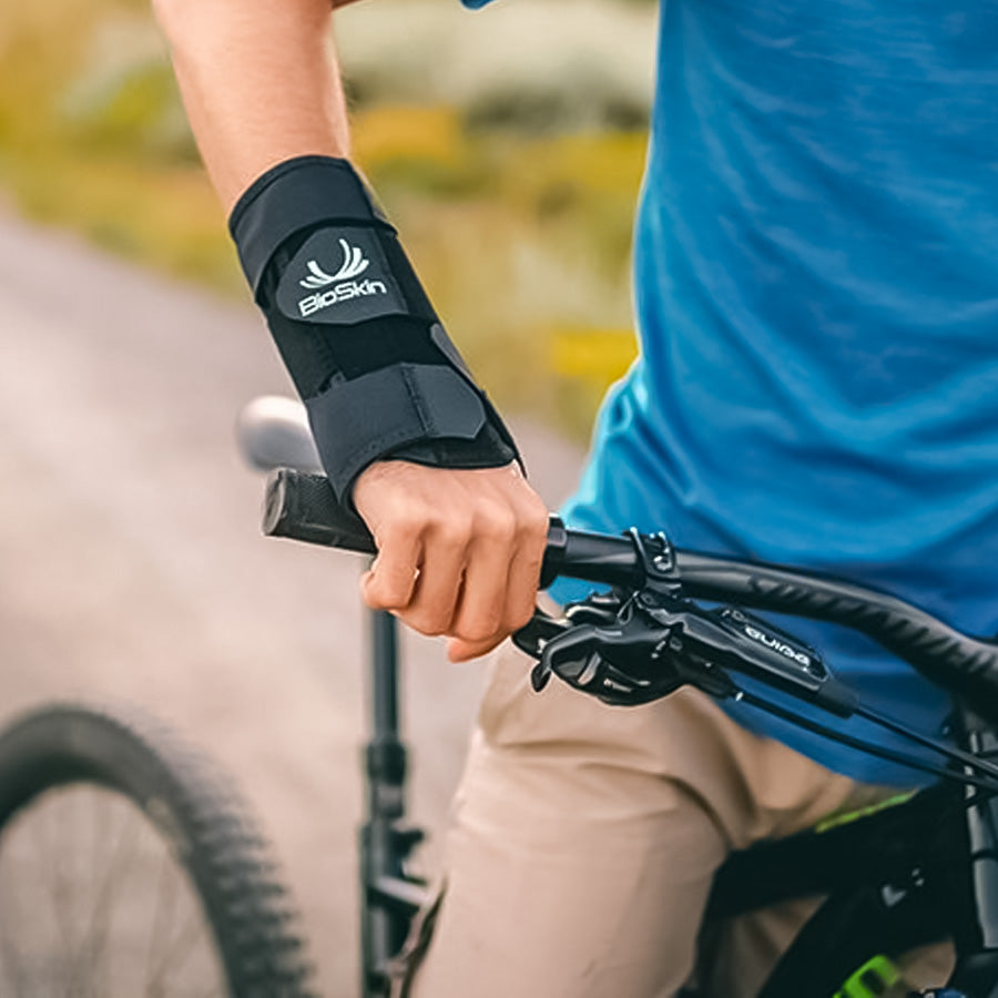 man biking while wearing the BioSkin Wrist Brace