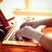 person wearing Incrediwear Fingerless Circulation Gloves while typing on their laptop