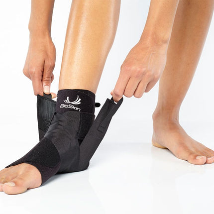 person adjusting BioSkin Premium Ankle Compression Brace 