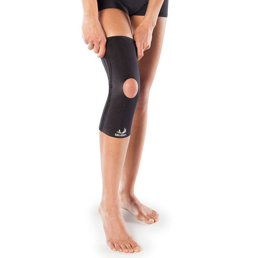 woman putting on BioSkin Knee Compression Sleeve